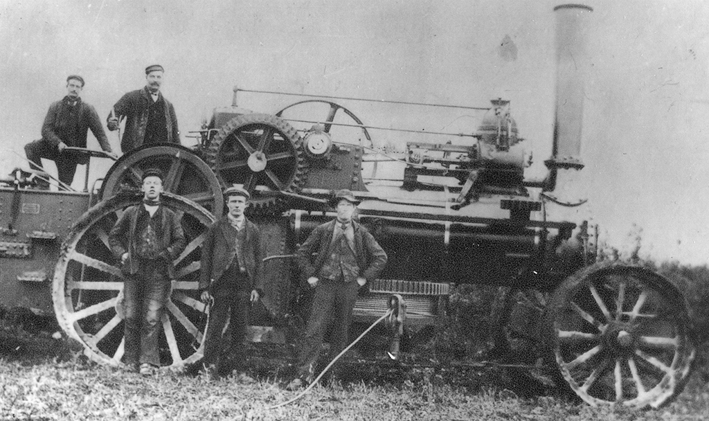 John Fowler Ploughing Engine No. 2898 or 2899 L. Briggs Jim Poreman the foreman is stood by the drum. The engine is stood showing the offside, the wire rope is stretched out in front of the engine. There are two men standing on the footplate and there in front of the engine. 