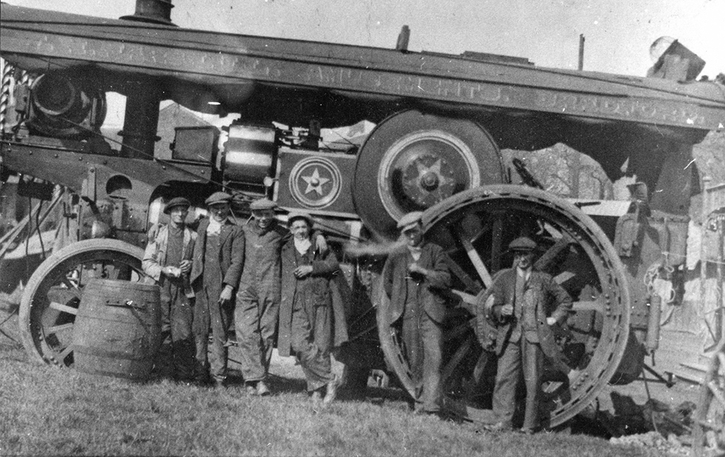 William Foster Showman's Road Locomotive No. 14403 named 'James-Walter' in ownership of W.H. Marshall, at Queensbury in 1934. The Showman's Road Locomotive is shown from the nearside. It is on a gradient with the front of the engine higher than it would normally be. There are six men posed, standing in front of the engine. The brass decoration is reflecting the sun brightly from the cylinder, and stars on the motion cover and flywheel.